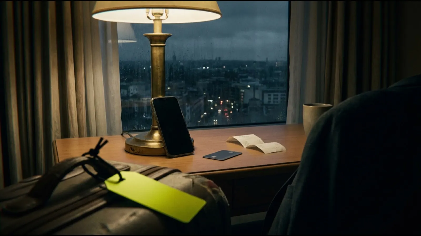 Ein Schreibtisch in einem Hotelzimmer bei Nacht mit einem an eine Lampe gelehnten Telefon