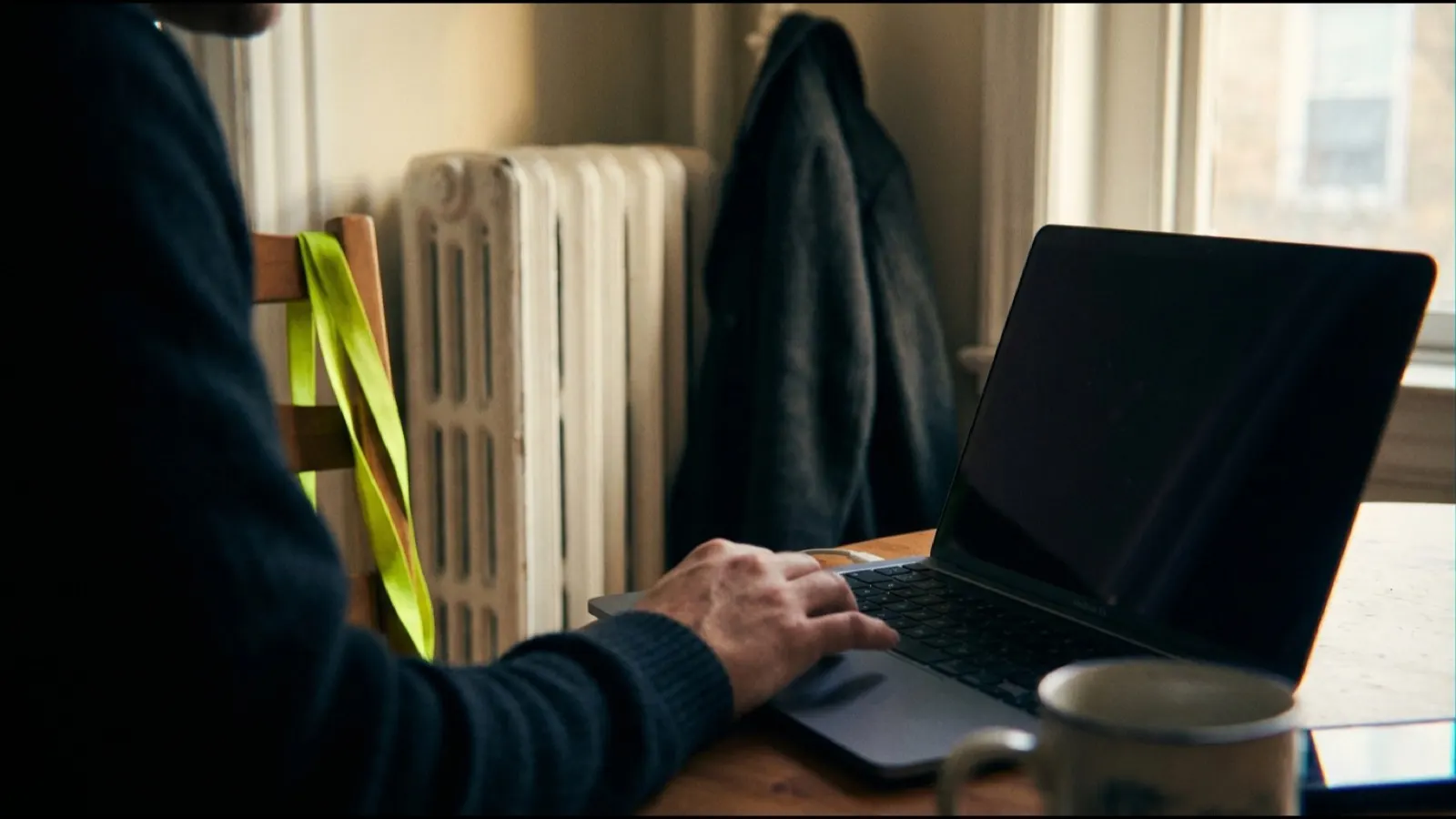 A hand on a laptop trackpad seen from behind