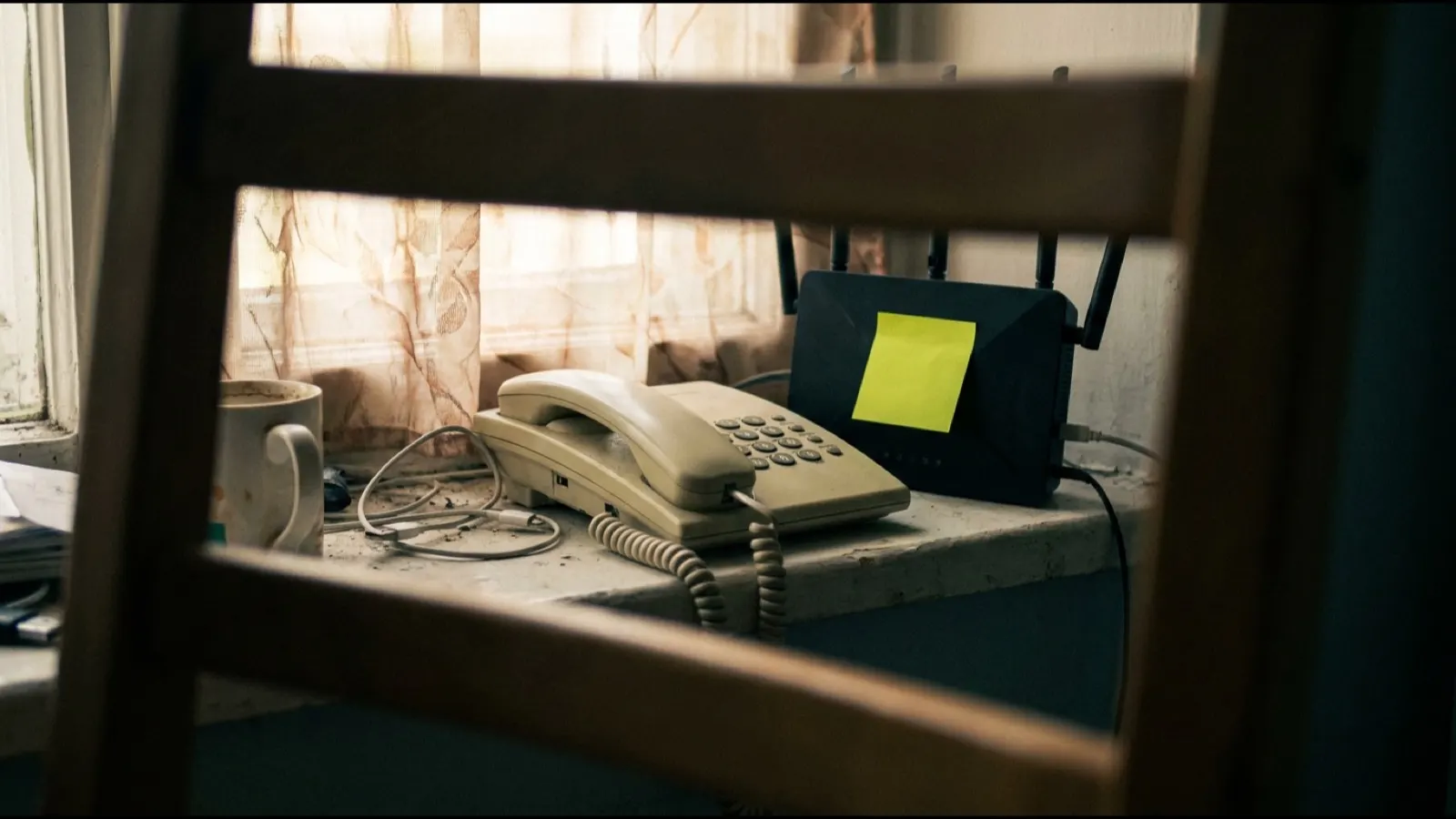 A corded desk telephone on a windowsill beside a router